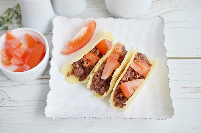 Keto Tacos - three keto tacos on a plate with tomatoes as garnish