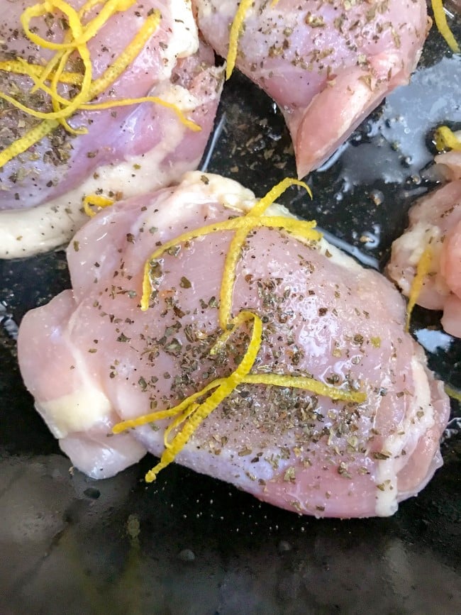 Lemon Basil Chicken Thighs - close up image of lemon zest and dried basil sprinkled on chicken 