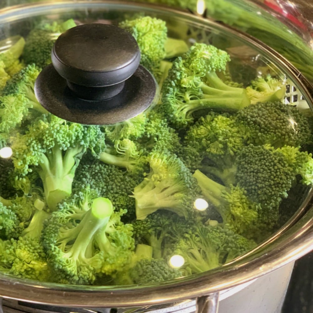 steaming broccoli on stove with lid
